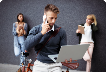 Man on a phone call outdoors holding a laptop