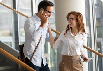 Two colleagues talking, one on a phone call